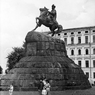 Equestrian statue with three people posing in front.
