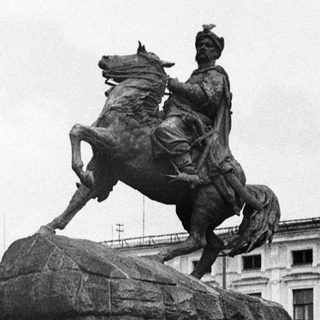 Equestrian statue with three people posing in front.