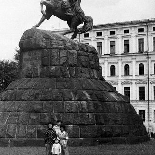 Equestrian statue monument with three people posing.