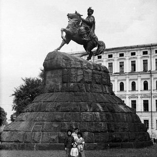 Equestrian statue monument with three people posing.
