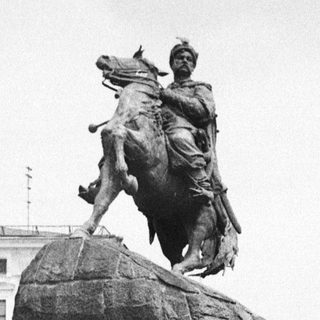 Equestrian statue on stone pedestal in park.