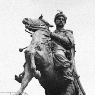 Equestrian statue on stone pedestal in park.