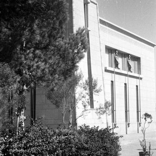 Historic building exterior with landscaped shrubs and potted plants.