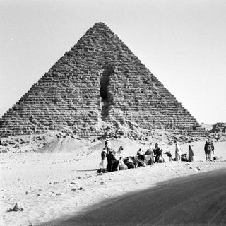Ancient pyramid with visitors and vehicles.