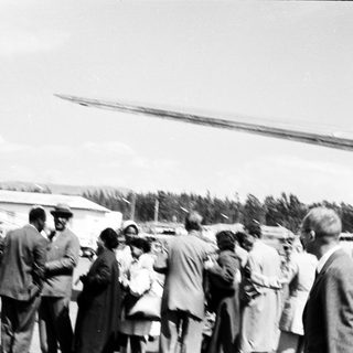 Group of people gathered near helicopter on rural airstrip.