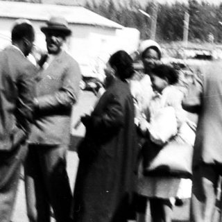 Group of people gathered near helicopter on rural airstrip.