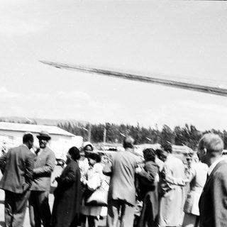 Group of people gathered near helicopter on rural airstrip.