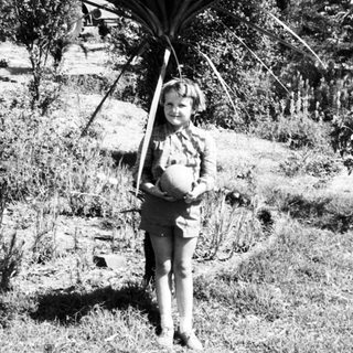 Child holding large palm frond outdoors.