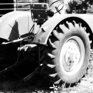 Vintage tractor plowing field with attached blade.