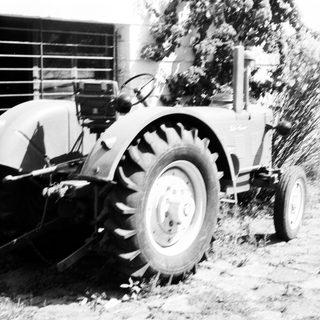 Vintage tractor plowing field with attached blade.