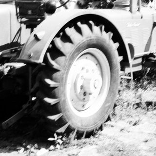 Vintage tractor plowing field with attached blade.