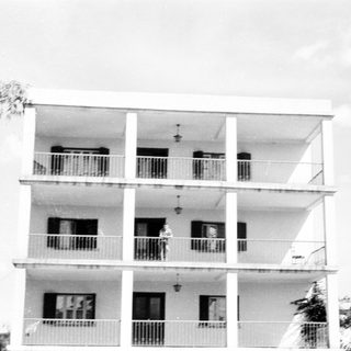 Three-story building with balconies, minimalist design.