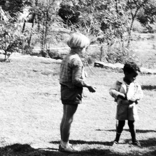 Children playing outdoors in a grassy area.