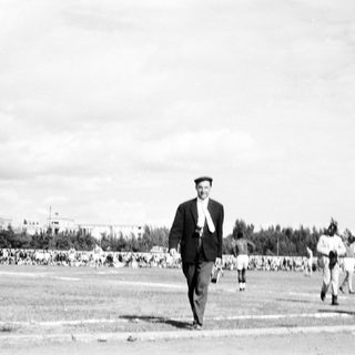 Man walking alone in large outdoor gathering.