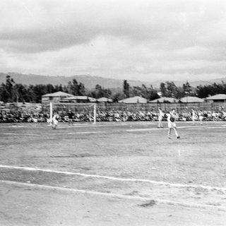 Black-and-white photo of men playing soccer on a field.