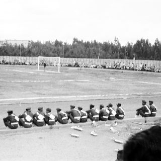 Group of men sitting on field during outdoor training session.