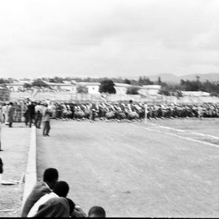 People observing large sandbag barrier near coastal area.