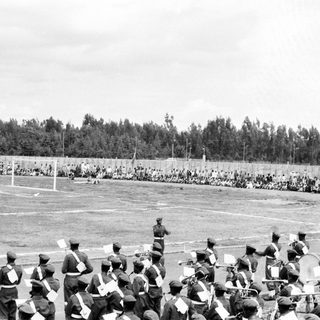 Military band parade with large crowd in stadium.