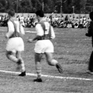 Football match in progress, vintage stadium crowd.