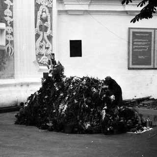 People tending to a large pile of offerings outside a building.