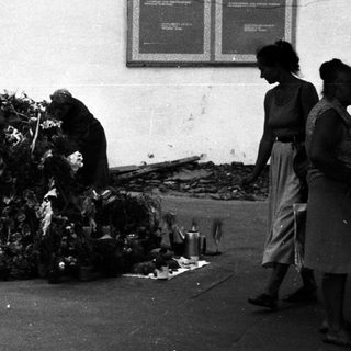 People tending to a large pile of offerings outside a building.