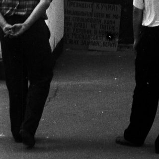 People standing near a closed door with a protest sign in Cyrillic.