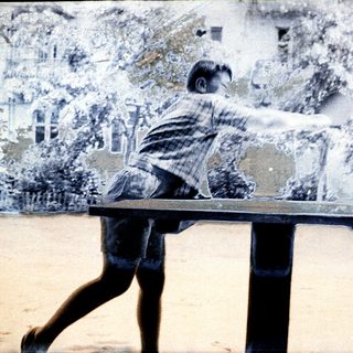 Boy playing table tennis outdoors.
