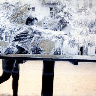 Boy playing table tennis outdoors.