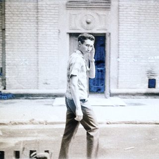 Young man talking on phone outside old building.