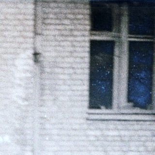 Young man talking on phone outside old building.