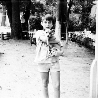 A child holding a small dog outdoors.