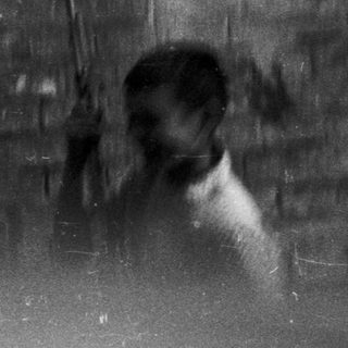 Blurred reflections of two people in a dimly lit room.