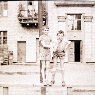 Two boys posing playfully outside an old building.