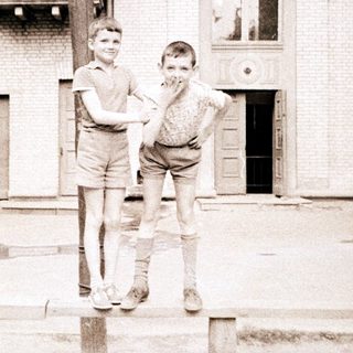 Two boys posing playfully outside an old building.