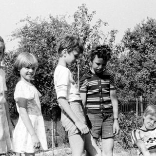 Five children and an adult outdoors in backyard.