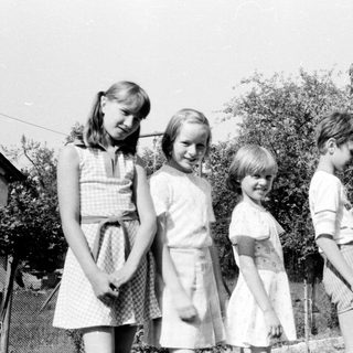 Five children and an adult outdoors in backyard.