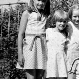 Five children posing happily outdoors in summer clothes.