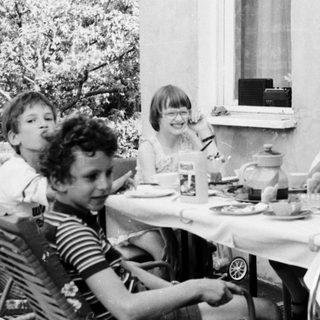Group of children eating outdoors at a table.