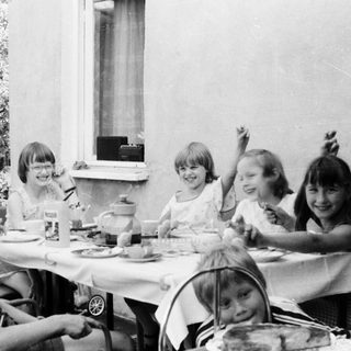 Group of children eating outdoors at a table.