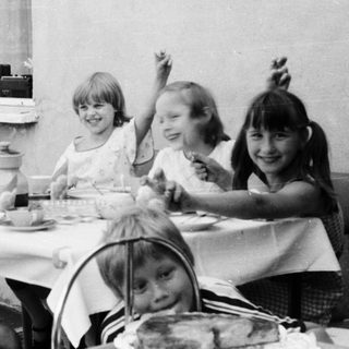 Group of children eating outdoors at a table.