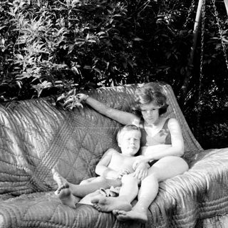Two people relaxing in a hanging chair outdoors.