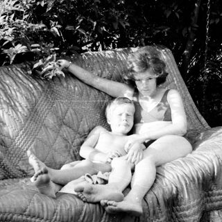 Two people relaxing in a hanging chair outdoors.
