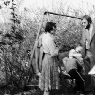 People outdoors in garden, possibly playing frisbee.
