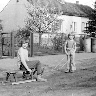 Two children playing with a homemade sled.