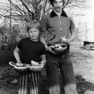 Two people carrying baskets of eggs outdoors.