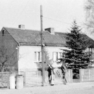 Two people playing frisbee near a house.