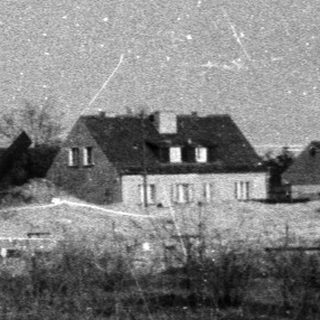 Rural landscape with houses and snow-covered fields.