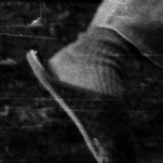 Person lying on a suspended mattress swing outdoors.