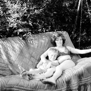 Mother and child relaxing in a hanging swing outdoors.