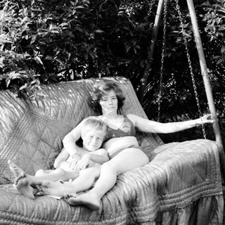 Mother and child relaxing in a hanging swing outdoors.